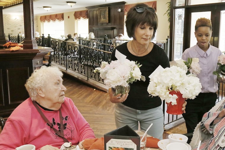Leona Davis (center) delivers flowers to residents at the Spring Hills Assisted Senior Living Facility in Cherry Hill on Sunday. Davis founded Forget Me Know Flowers, a Haddonfield-based nonprofit that transforms wedding flowers into "bedside bouquets" for residents of nursing homes and hospitals. ELIZABETH ROBERTSON / Staff Photographer