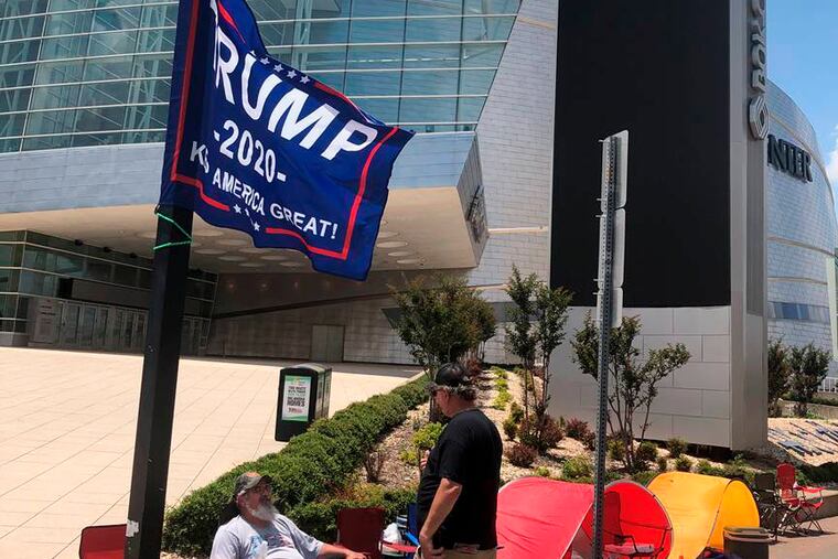 James Massery, left, of Preston, Okla., and Daniel Hedman, of Tulsa, Okla., supporters of President Donald Trump, camp outside the BOK Center in Tulsa four days before his scheduled rally Saturday. President Donald Trump's campaign says six staff members helping set up for his Saturday night rally in Tulsa, Oklahoma, have tested positive for coronavirus.