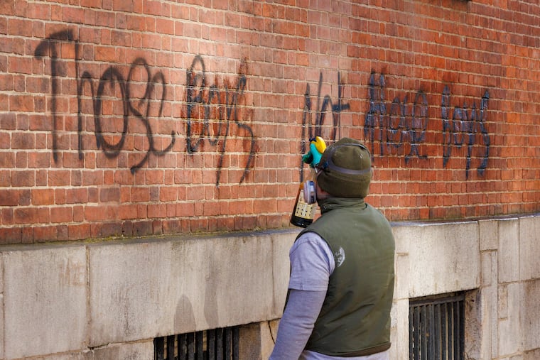 A National Parks Service worker sprays graffiti for removal on side of Congress Hall, Philadelphia Independence Hall, on Jan. 17. It reads, “Those Boys Not these Boys.”
