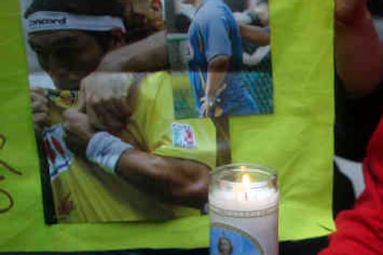Fans of the Mexican soccer team America holds a candle and a sign with images of Paraguayan soccer player Salvador Cabanas outside of a hospital in Mexico City.