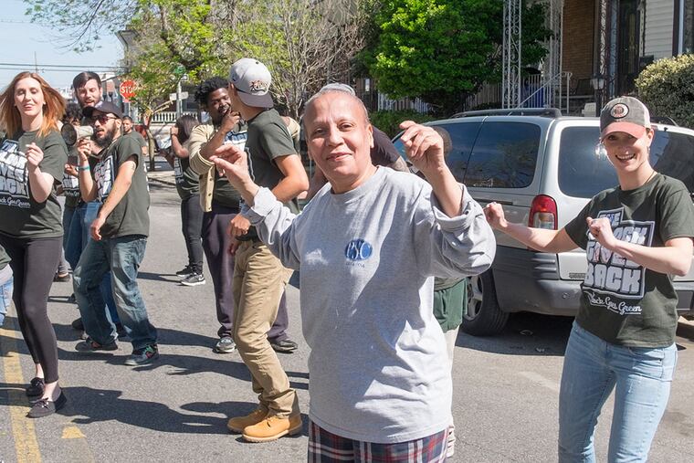 Resident Judy Eberhart (front center) dances with volunteers as a block party begins.