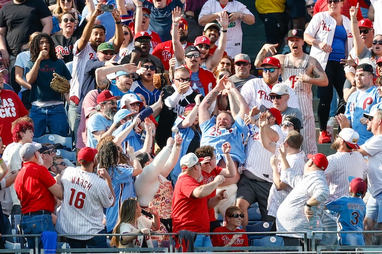 Phillies fans reach for Kyle Schwarber's first-inning two-run homer on opening day Thursday at Citizens Bank Park.