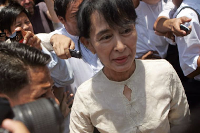 Myanmar pro-democracy leader Aung San Suu Kyi, right, leaves her National League for Democracy party after a meeting at the party's headquarters Friday, April 20, 2012, in Yangon, Myanmar. After opposition leader Aung San Suu Kyi's party swept special elections this month, the Obama administration said it would ease restrictions on financial services and investment. (AP Photo/Khin Maung Win)