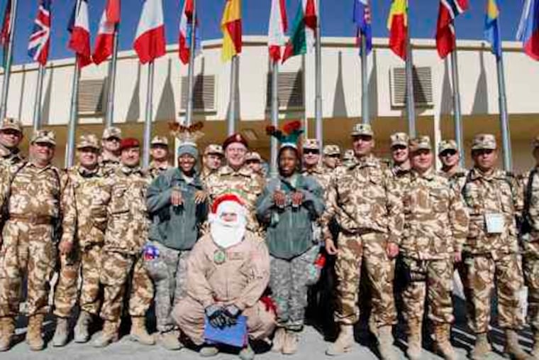 Soldiers of the NATO-led International Security Assistance Force join Santa Claus - a U.S. soldier beneath the costume - at Camp Phoenix. The troops celebrated Christmas with food, music, and improvisation.