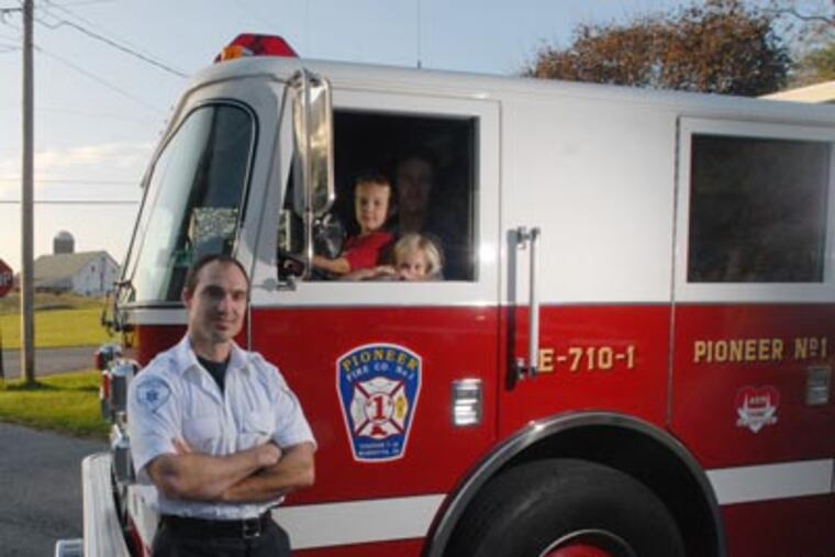 At Pioneer Fire Company No. 1 in Marietta, Pa., Jon Merrell (left) poses with Megan Lauver, 6, Justin Lauver, 8, and their father, Miles Lauver. (Bob Williams / For the Inquirer)