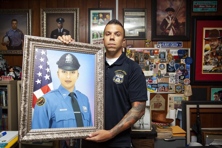 Officer Johnny Castro, a forensic composite artist for the Philly PD, poses for a portrait while holding a digital painting of Isabel Nazario, who died a year ago, at Philadelphia Police headquarters on Thursday, Sept. 06, 2018. Castro creates a digital portrait of police officers (including police dogs) who die in the line of duty around the U.S. and sends a copy for free to the family.