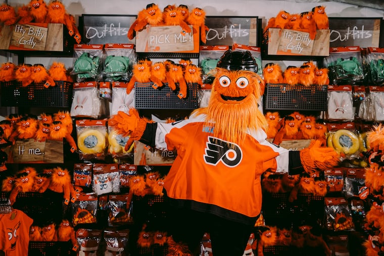 Gritty stands inside his new store at the Wells Fargo Center, Gritty's Chaos Factory, surrounded by customizable Itty Bitty Gritty dolls for purchase.