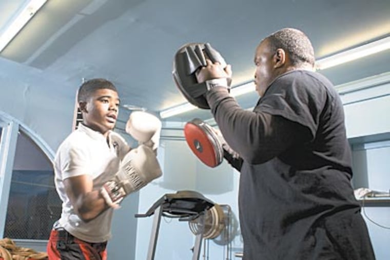 "(Men) need to come out from behind the curtains and skirts and get out there," says Men of Tustin president James Haley. Here, Anwar Jones, 15, learns how to box with William Edney. (ED HILLE / Staff)