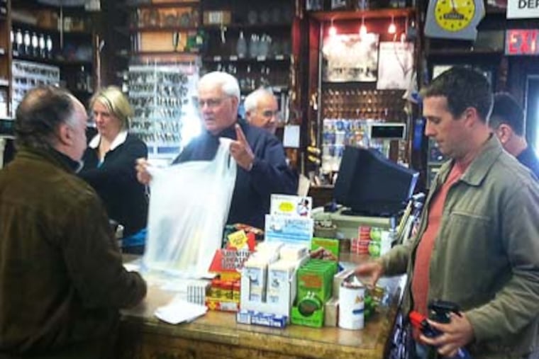 Dave Callahan makes a sale while Andy Smith (right) waits to make a purchase at Newtown Hardware House on Saturday morning. (Bill Reed/Staff)