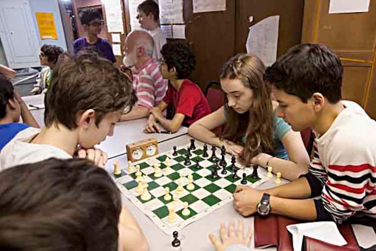Masterman Middle School's award-winning chess team has their most recent triumph , the national championship. Photographed at school on Thursday April 11th, Alex Wlezien, 14, left, and Shira Moolten,13, right face off in a chess match in the basement of Masterman Middle School as they are watched by teammates including Alejandro Budejen-Jerez, far right and Torin Kuehnle, far left. ( ED HILLE / Staff Photographer )