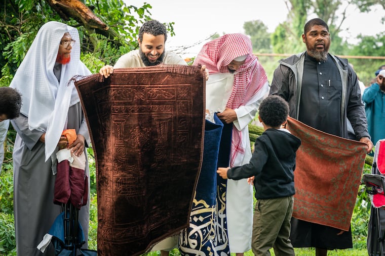 (Left to Right) Shaykh Talhah, Imam Hassan Abdi of Germantown Masjid, Anwar Wright, and President of Germantown Masjid Isa Underdue, put down their prayer rugs prior to pray during Eid al-Adha at Fern Hill Park.