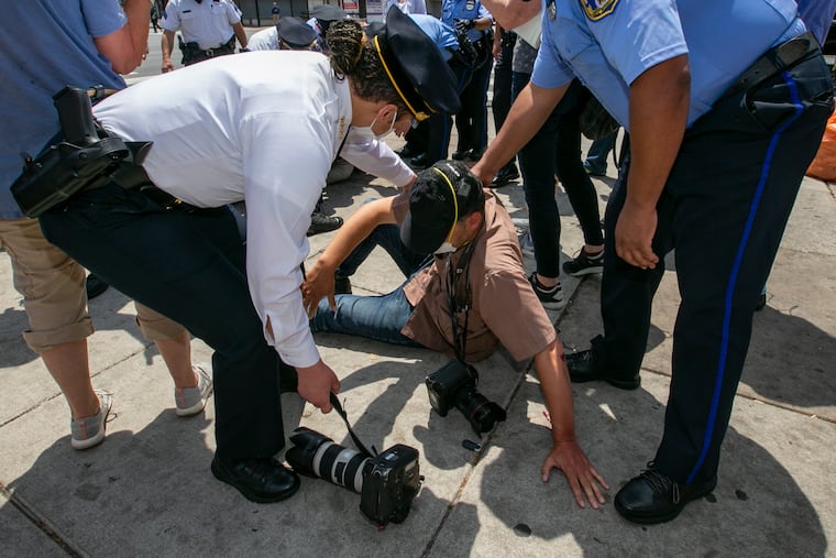 A news photographer was assaulted while touring the business district at Broad and Erie with the Police Commissioner and Mayor. Police Commissioner Danielle Outlaw (left) attends to the photographer as he sits on the sidewalk at Broad St. at Avenue in Philadelphia on Thursday.