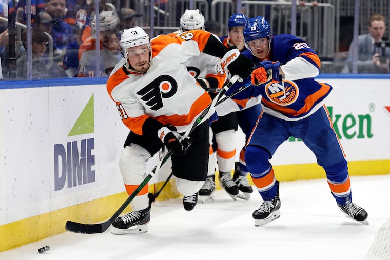 Philadelphia Flyers defenseman Justin Braun (61) skates with the puck past New York Islanders right wing Hudson Fasching in the second period of an NHL hockey game Saturday, April 8, 2023, in Elmont, N.Y. (AP Photo/Adam Hunger)
