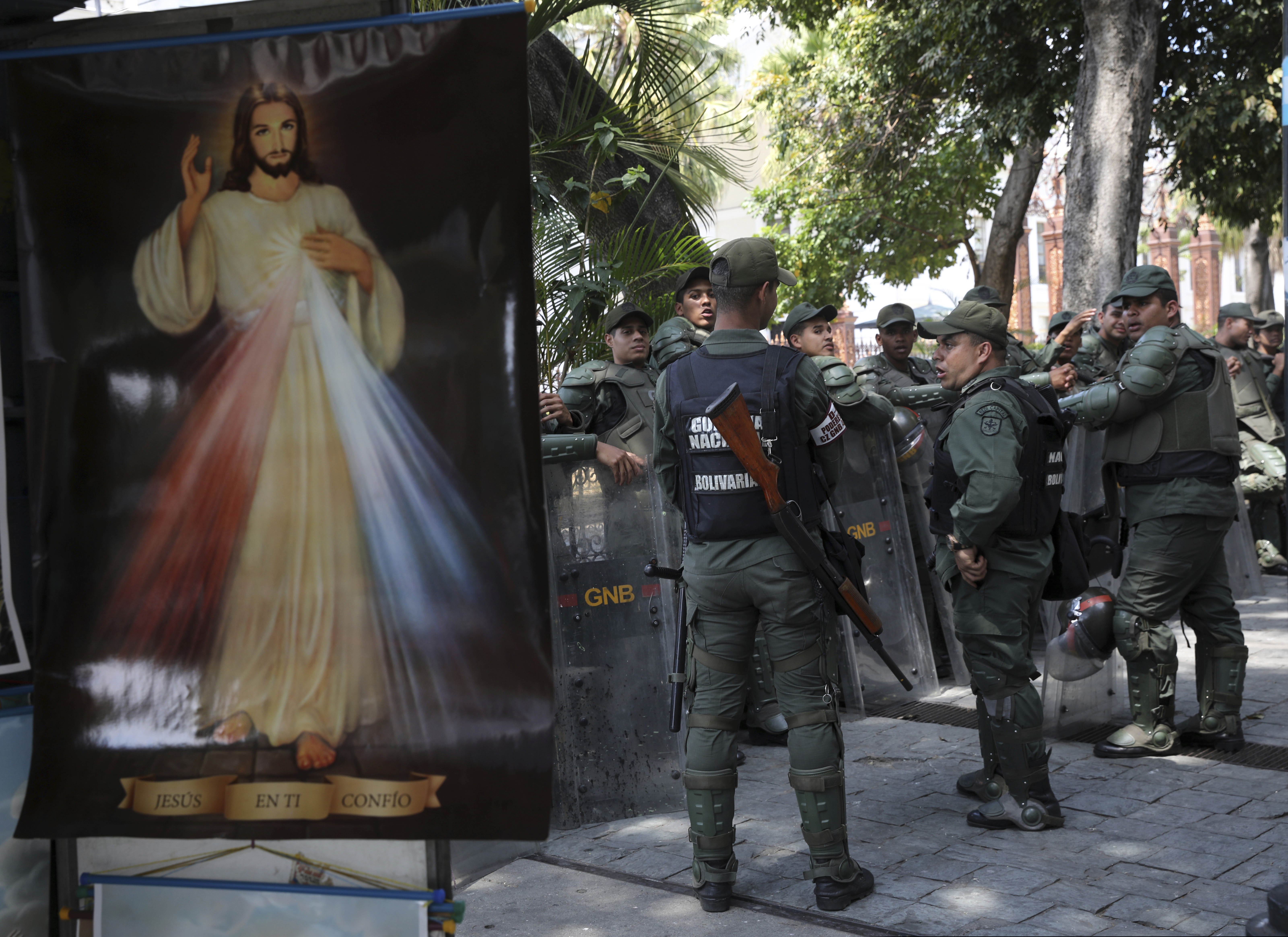 Venezuelan Bolivarian National Guardsmen line up near a Divine Mercy Jesus Christ poster outside the National Assembly in Caracas, Venezuela, Tuesday, Jan. 29, 2019.