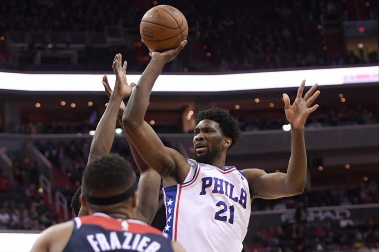 Joel Embiid shoots as Wizards guard Tim Frazier (8) watches during the first half.