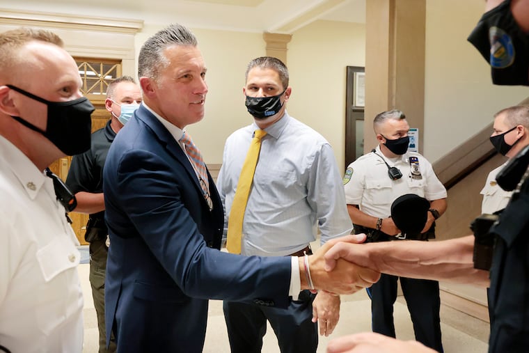 Upper Darby Police Superintendent Timothy Bernhardt (second from left) is greeted by members of law enforcement after being sworn in during a township council meeting in September. Bernhardt says his priority is to adopt a more community-driven approach to policing.