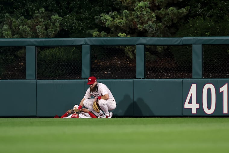 Brandon Marsh checks on teammate Derek Hill after he was hurt making a play on a fly ball in the 11th inning.