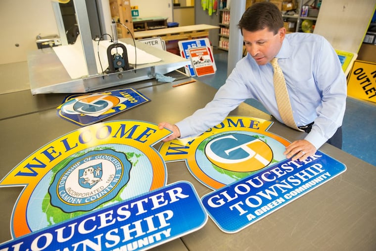 Gloucester Township Mayor David Mayer shown with the old and new township signs.