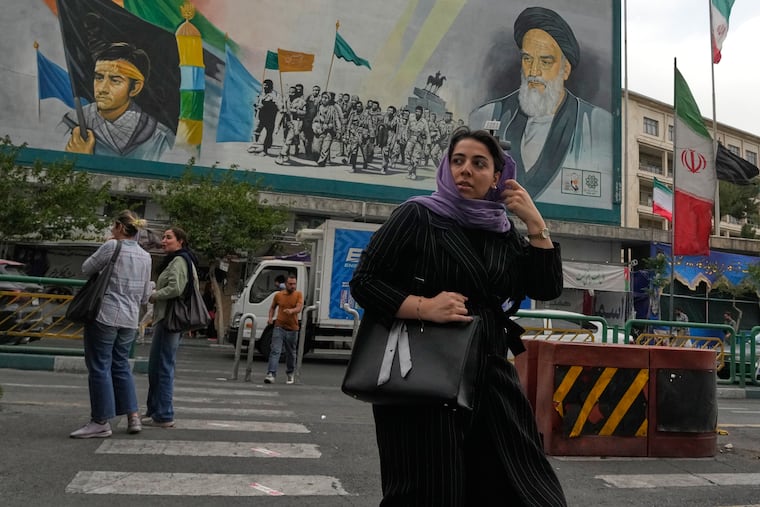 A woman crosses a street in front of a painting of the late Iranian revolutionary founder Ayatollah Khomeini in downtown Tehran, Iran, last month.