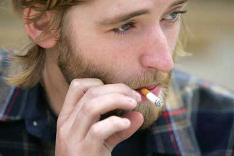 Kris Jackson, an anthropology major at West Chester University illegally enjoys a smoke outside of Sykes Student Union Center. (David Swanson/Inquirer)