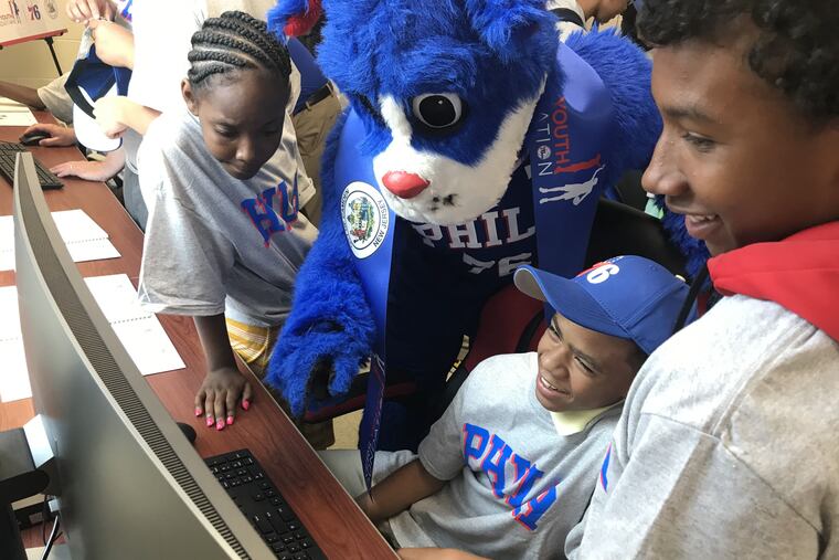 Children and the 76ers mascot check out the computers at the new education center in Camden that the team funded.