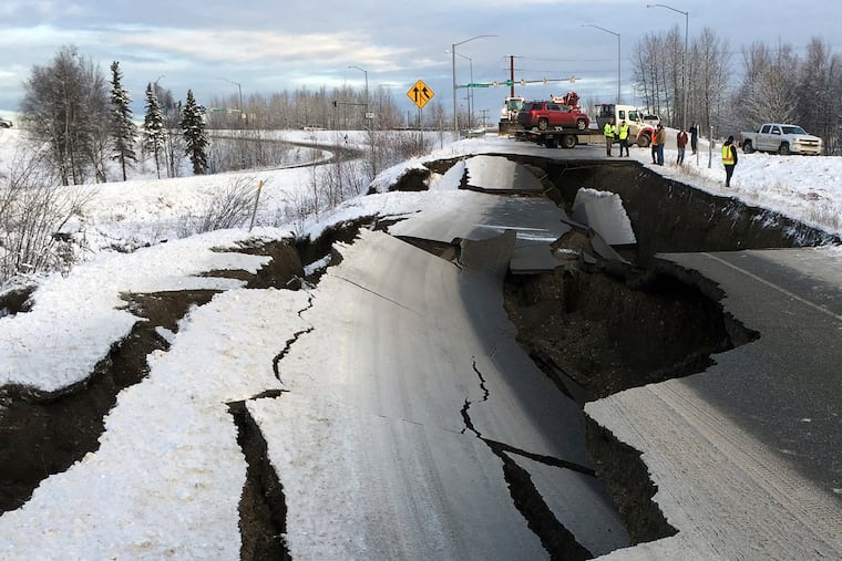 A tow truck holds a car that was pulled from on an off-ramp that collapsed during a morning earthquake on Friday, Nov. 30, 2018, in Anchorage, Alaska. The driver was not injured attempting to exit Minnesota Drive at International Airport Road. Back-to-back earthquakes measuring 7.0 and 5.8 rocked buildings and buckled roads Friday morning in Anchorage, prompting people to run from their offices or seek shelter under office desks, while a tsunami warning had some seeking higher ground. (AP Photo/Mike Dinneen)