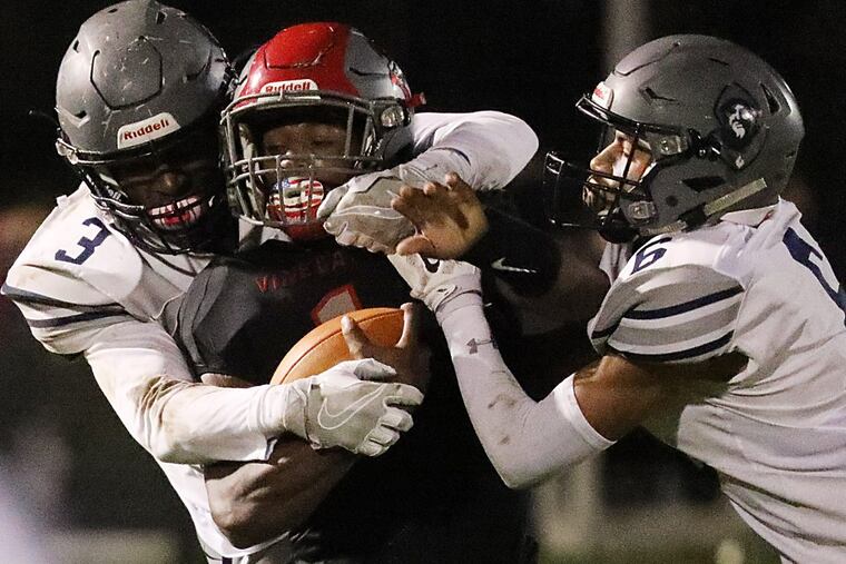 Vineland QB Isaih Pacheco is tackled by St. Augustine’s Xavier File (left) and Sincere Rhea.