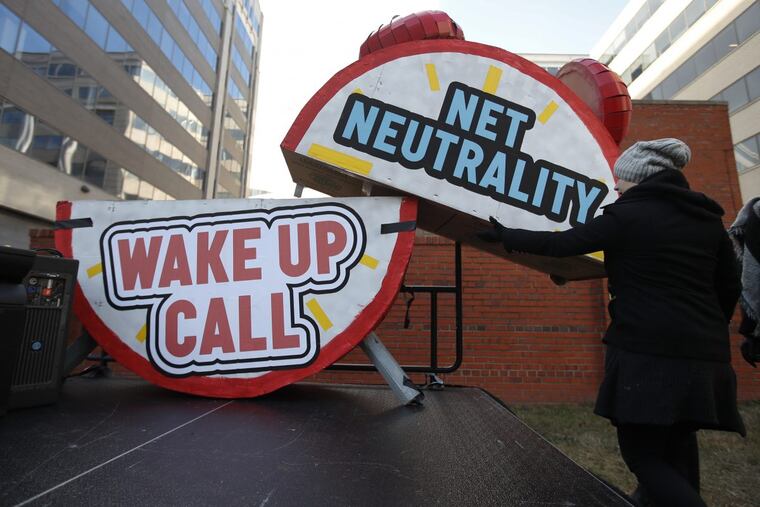 Sammi LeMaster helps to dismantle a large alarm clock display after a protest at the Federal Communications Commission Thursday.