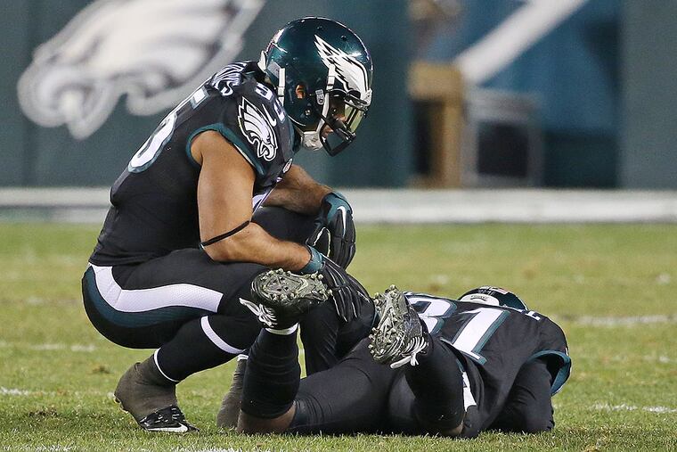Mychal Kendricks (left) checks on an injured Byron Maxwell.