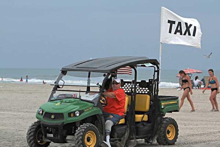 In Wildwood City, beach officials test their hands at a new program, beach taxi service. Beachgoers can now avoid the cumbersome walk to the water, at points, a quarter-mile hike, for a small fee. Jim Kenny waits in a John Deer Gator on the beach looking for customers on July 24, 2014. ( CHARLES FOX / Staff Photographer )