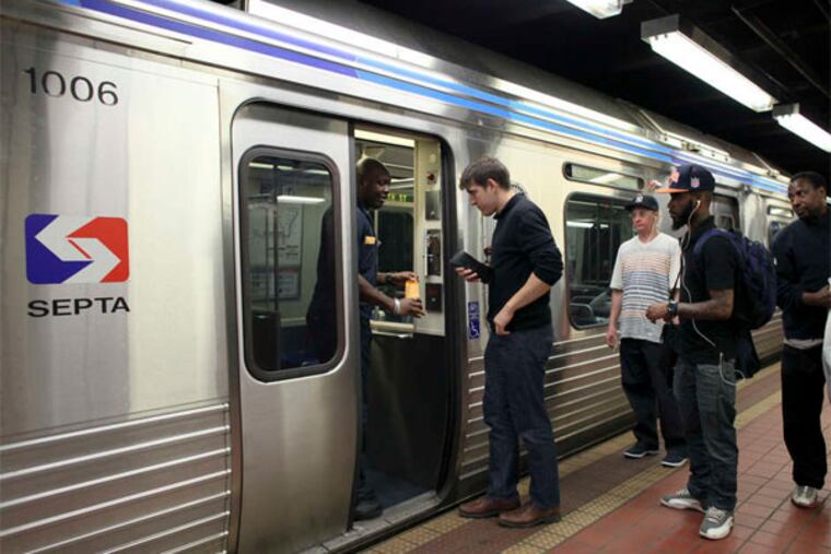 SEPTA rail operator Maurice Bey (left) collects fares from passengers boarding the Market-Frankford Line. (Joseph Kaczmarek / For the Daily News)