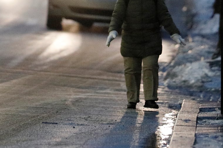 A woman walks carefully on Fifth Street in Center City Philadelphia Saturday evening. A winter weather advisory calls for freezing rain and ice Monday and Tuesday.