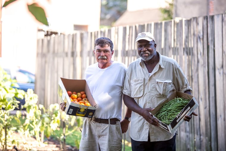 John Lindsay and James Seward stand with fresh produce from Wiota Street Community Garden, which was saved by the Philadelphia Redevelopment Authority last year.