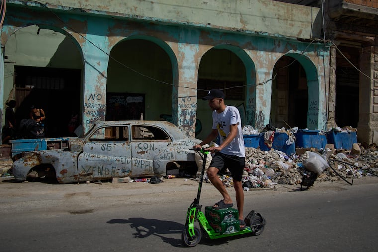 A man rides a scooter past a wrecked car and piles of garbage during a blackout in Havana on March 4.