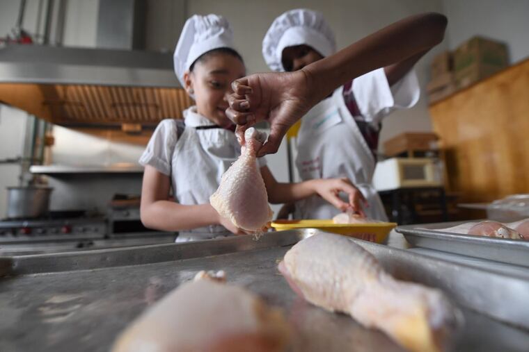 Destiny Vera (left) and Quinterra Phillips make chicken during the My Daughter’s Kitchen cooking class at St. Martin of Tours School.