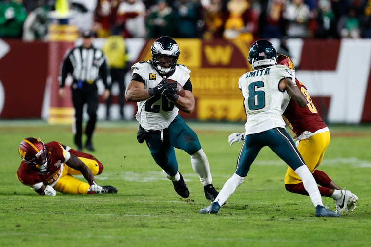 Eagles running back Saquon Barkley breaks off a 48-yard run as receiver DeVonta Smith blocks Washington's Jonathan Jones on Saturday night.