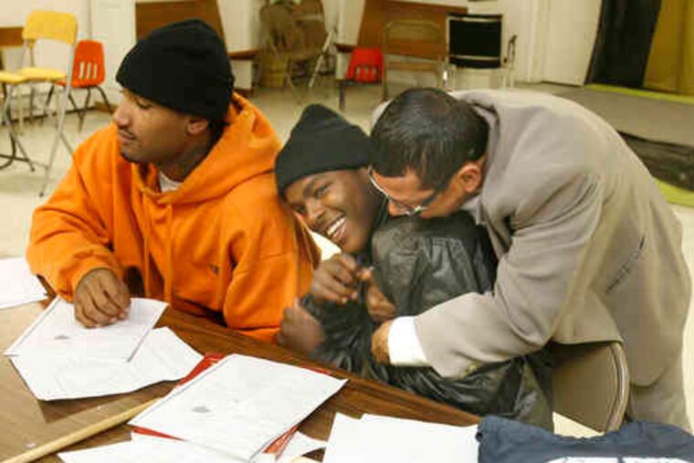 Student Alieu Bhah gets a playful hug from Angel Cordero, cofounder of the Community Education Resource Network and East Side Prep programs. Next to them is Alfred Taylor.