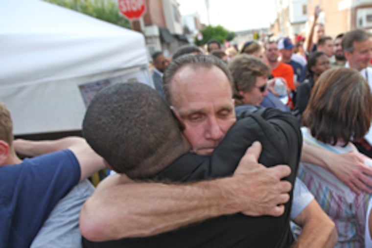 Floyd Liczbinski, facing the camera, hugs Try Baylor, a community activist, at a vigil yesterday for slain Philadelphia Police Sgt. Stephen Liczbinski. (Michael Bryant / Inquirer)