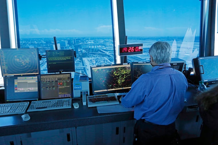 In this 2013 photo, an air traffic controller works in front of computer screens and a digital clock showing Coordinated Universal Time (UTC) in the control tower at Los Angeles International Airport.