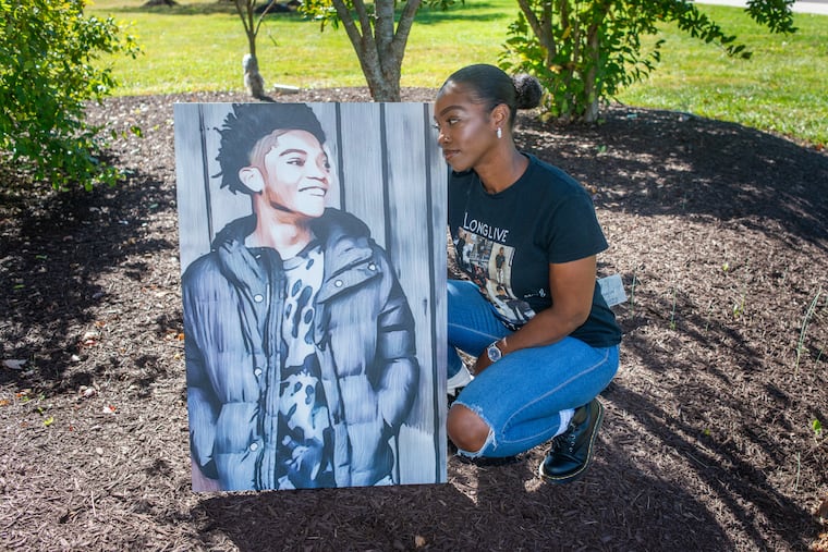 Cherisse Pearson poses near a tree planted in honor of her son, Theodore "Tre" Crawford, with a portrait of him at North Montco Technical Career Center in Towamencin, Pa.