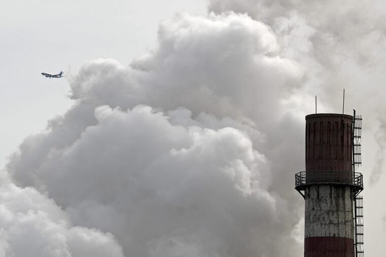 In this Feb. 28, 2017 file photo, a passenger airplane flies behind steam and white smoke emitted from a coal-fired power plant in Beijing.