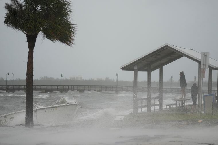 People brave rain and heavy winds to visit the waterfront along the Jensen Beach Causeway, as conditions deteriorate with the approach of Hurricane Nicole, Wednesday, Nov. 9, 2022, in Jensen Beach, Fla.