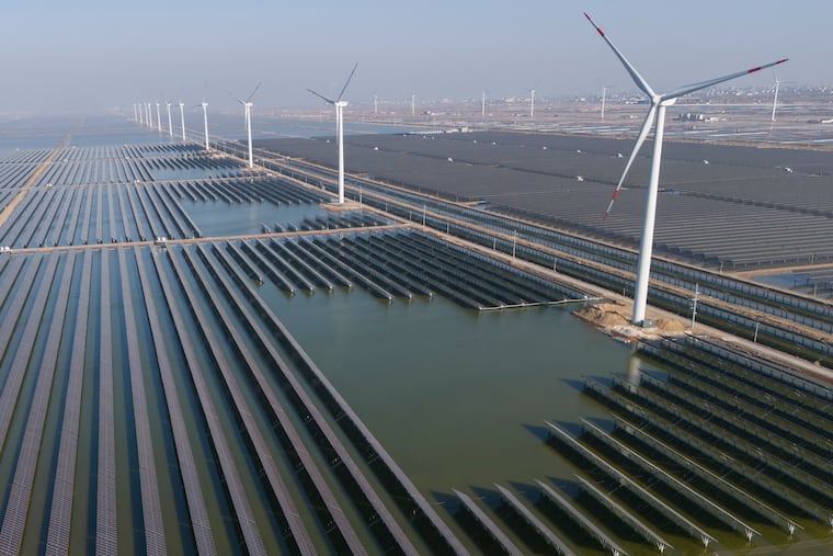 Wind turbines operate along a solar farm in eastern China's Shandong province.