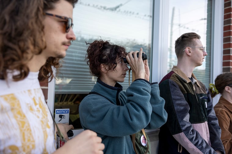 Avery Breyne-Cartwright, of West Philadelphia, using binoculars to look at the flock of pigeons on the power lines along Sixth Street and Washington Avenue during a Philly Pigeon Tour.