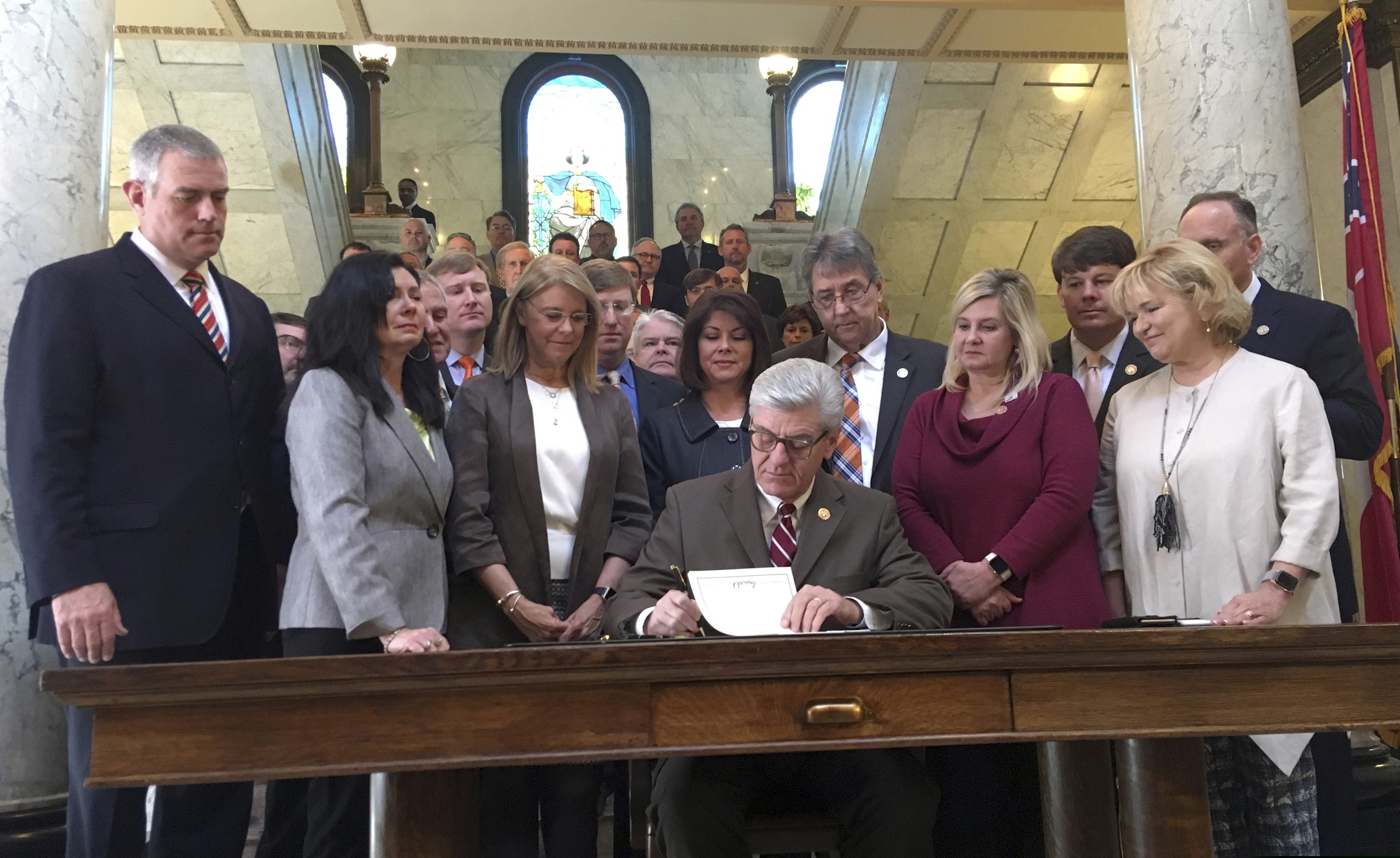 Mississippi Gov. Phil Bryant is surrounded by lawmakers on Thursday, March 21, 2019, as he signs a bill that would ban most abortions once a fetal heartbeat can be detected, at the capitol in Jackson, Miss. The bill is set to become law July 1, 2019 and would be one of the strictest abortion laws in the nation. The Center for Reproductive Rights calls the law unconstitutional and says it will sue Mississippi to try to block the law from taking effect.