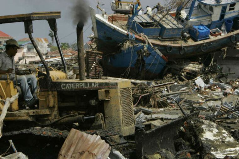 Weeks after the Dec. 26, 2004, tsunami, a bulldozer cleared rubble in front of a ship swept ashore in Indonesia. PETER DEJONG / Associated Press