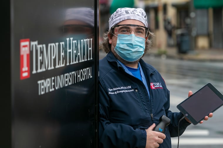 Temple physician Ryan Gibbons holding the Butterfly iQ a portable ultrasound device used for rapid diagnosis of pneumonia in COVID-19 patients.