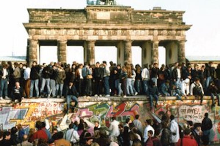 East and West Germans stood together on the Berlin Wall in front of the Brandenburg Gate on Nov. 10, 1989, a day after the wall opened.