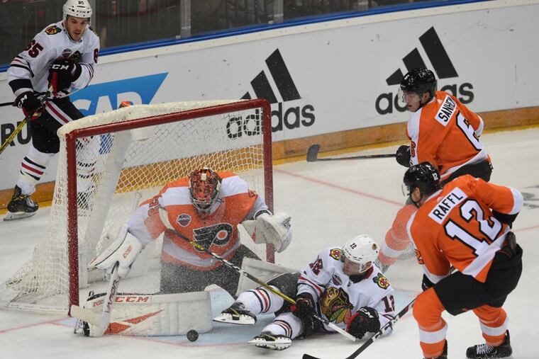 Goalie Carter Hart vies for the puck with Chicago's Alex DeBrincat, while Michael Raffl (12) and Travis Sanheim (far right) converge during the NHL Global Series game Friday, won by the Flyers in Prague, 4-3.