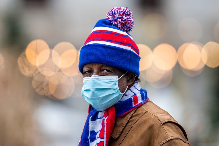 An unidentified man shields his face from the wind and cold temperatures in Center City in December 2020.